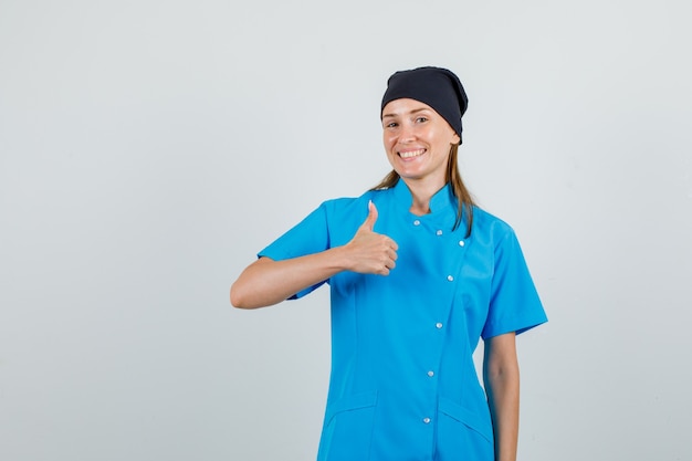 Female doctor in uniform showing thumb up and smiling and looking pleased