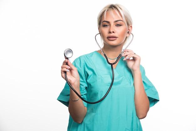 Female doctor using stethoscope on white surface