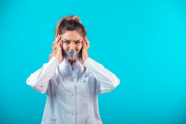 Free photo female doctor in white uniform covering her mouth and ears.