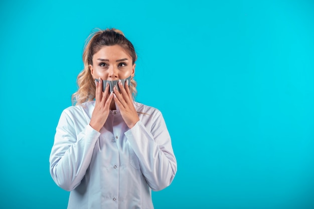 Female doctor in white uniform covering her mouth .