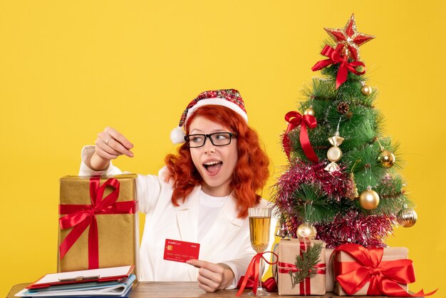 female doctor with present and bank card on light yellow