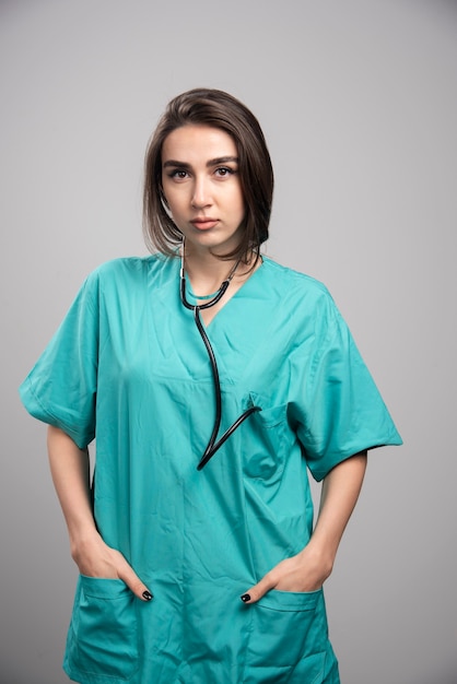 Female doctor with stethoscope standing on gray background. High quality photo