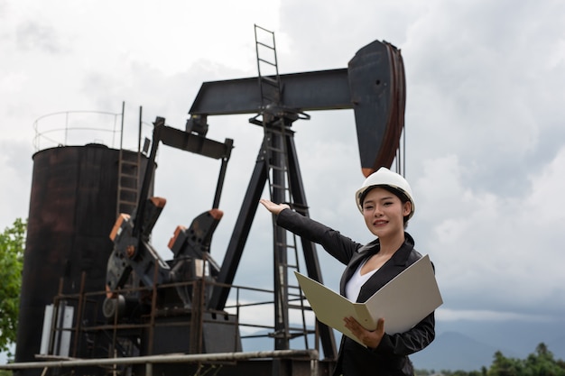 Free Photo female engineer standing beside working oil pumps with a sky .