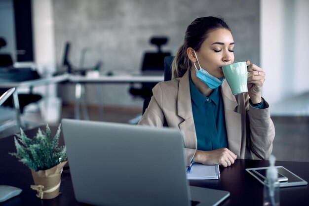 Female entrepreneur enjoying in cup of fresh coffee in the office