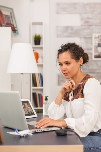 Female entrepreneur looking at laptop while working from home office.