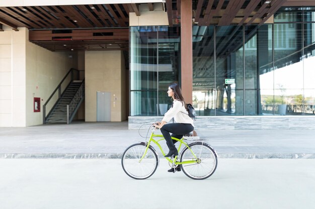 Female environmentalist riding bicycle on street against office building