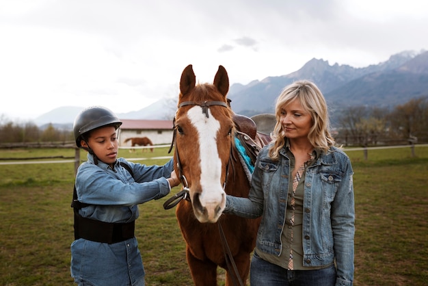 Free photo female equestrian instructor teaching child how to ride horse