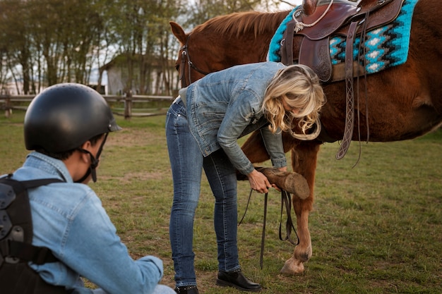 Free photo female equestrian instructor teaching child how to ride horse