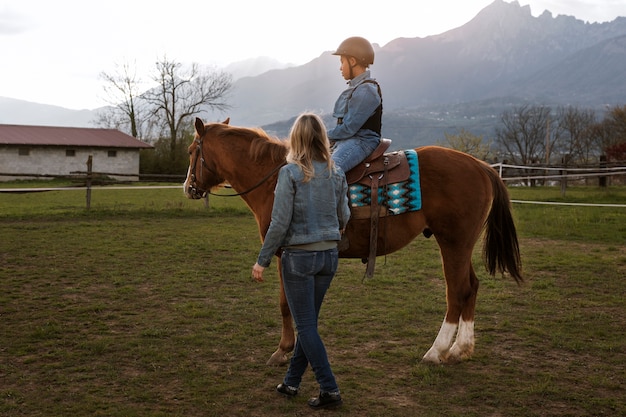 Female equestrian instructor teaching child how to ride horse