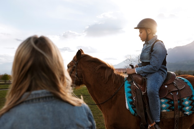 Female equestrian instructor teaching child how to ride horse