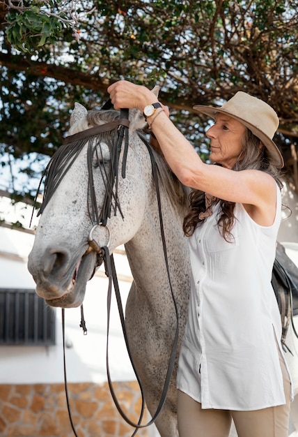 Free photo female farmer equipping her horse at the ranch