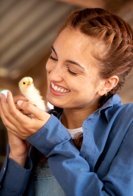 Free Photo female farmer holding a baby chicken