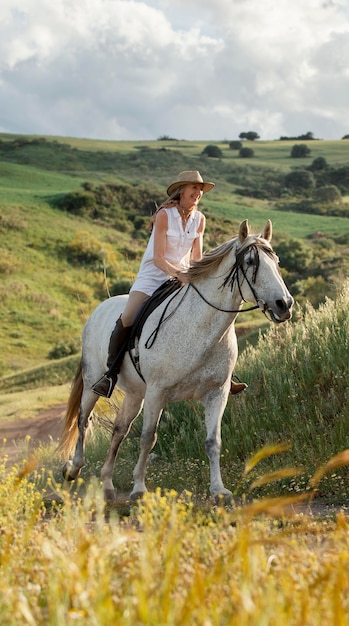 Free photo female farmer horseback riding in nature outdoors