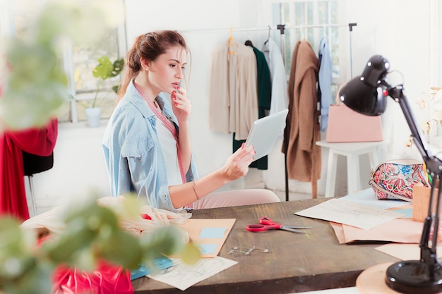 Free photo the female fashion designer working in studio sitting on the desk