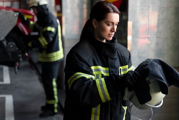 Free photo female firefighter putting on safety helmet