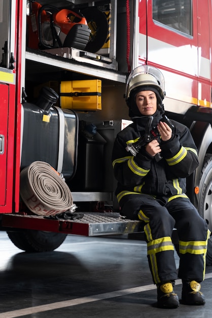 Free photo female firefighter at station equipped with suit and safety helmet