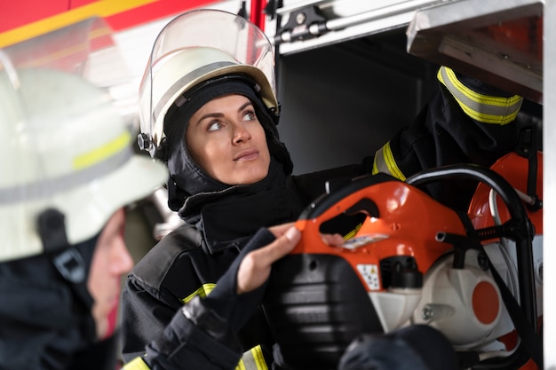 Free photo female firefighter at station equipped with suit and safety helmet