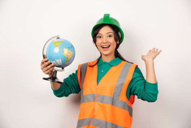 Female firefighter with globe feeling happy on white background.