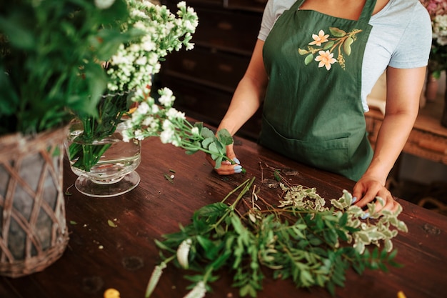 Free Photo female florist holding bunch of fresh white flowers over wooden desk