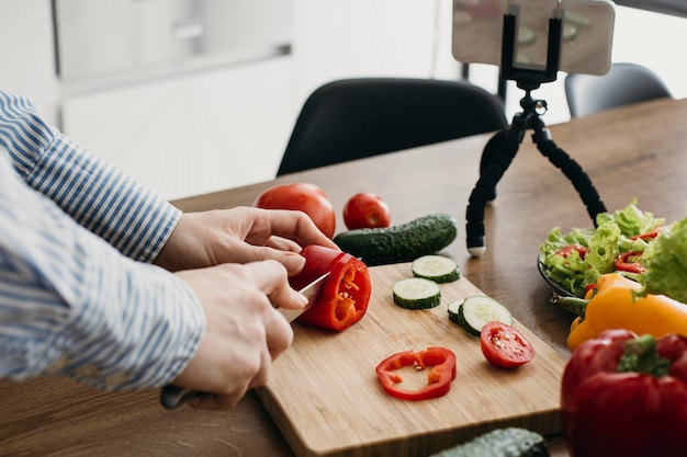 Female food blogger streaming with smartphone at home while cooking