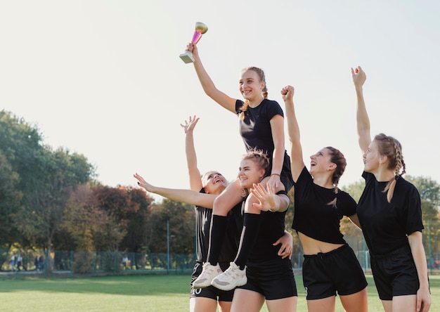 Free photo female football players winning a trophy