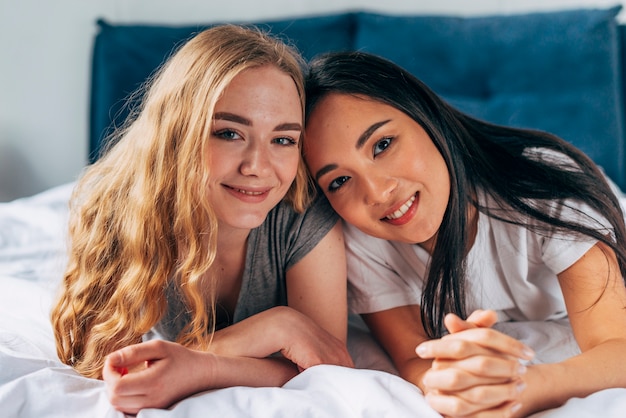 Free Photo female friends on bed looking at camera