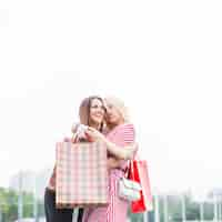 Free photo female friends holding shopping bags embracing each other