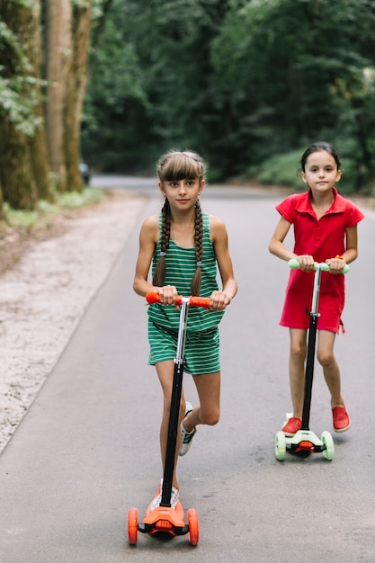 Female friends riding scooter on road