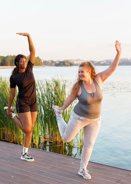 Female friends stretching together by the lake