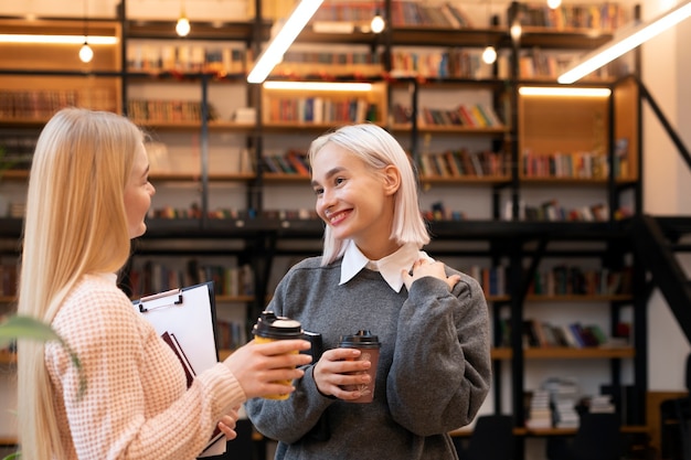 Female friends taking books from a library to use in a study session