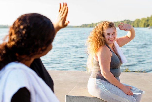 Female friends waving at each other after working out