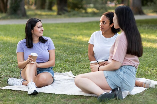 Female friends with coffee together at the park