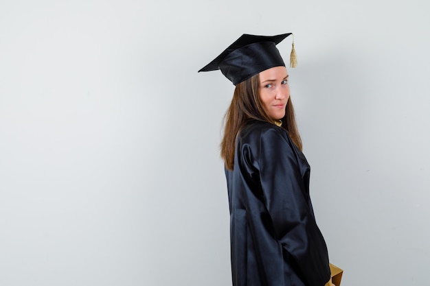 Free photo female graduate looking at camera in academic dress and looking sensible .