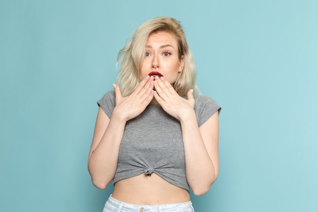 Free Photo female in grey shirt and bright blue jeans posign with surprised expression