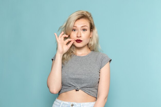 female in grey shirt and bright blue jeans posing with silent expression