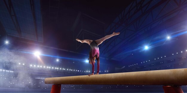 Female gymnast doing a complicated trick on gymnastics balance beam in a professional arena