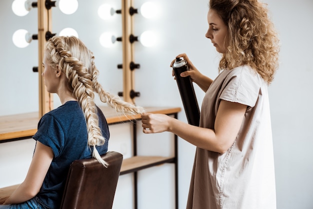 Free photo female hairdresser making hairstyle to blonde woman in beauty salon