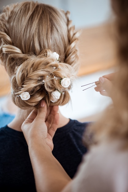 Free photo female hairdresser making hairstyle to blonde woman in beauty salon