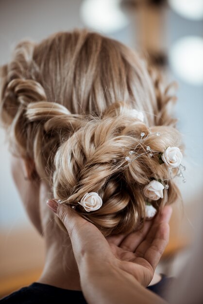 Female hairdresser making hairstyle to blonde woman in beauty salon