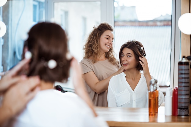 Female hairdresser and woman smiling looking in mirror in beauty salon