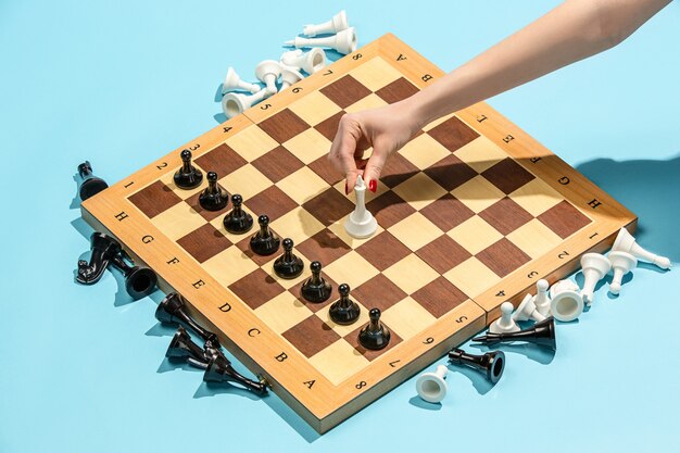 Female hand and chess board, game concept.