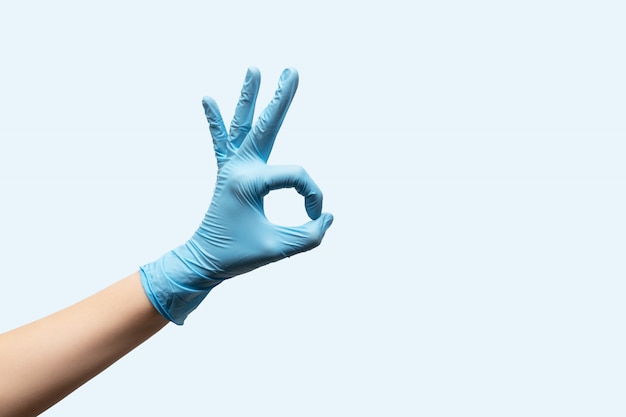 Free photo female hand in disposable gloves on light blue background.