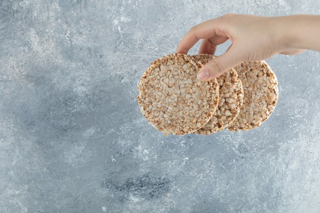 Female hand holding airy crispbread on marble surface