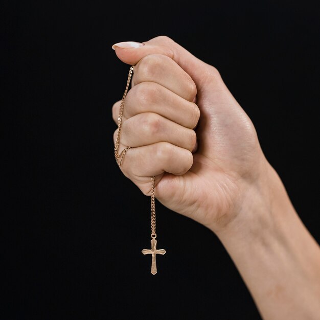 Female hand holding cross necklace