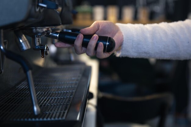 A female hand holds a holder in a professional coffee machine