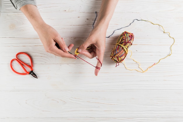 Free photo female hand knitting with colorful wool on wooden table