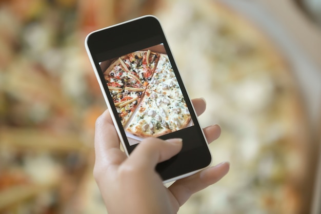 Free photo female hand making a photo of pizza