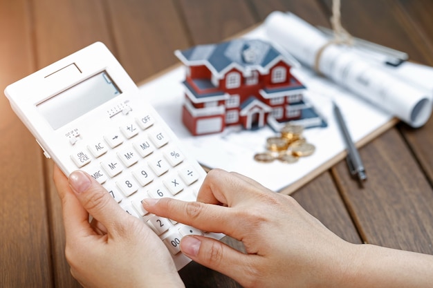 Free photo a female hand operating a calculator in front of a villa house model