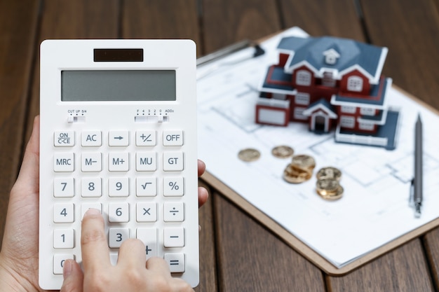 Free Photo a female hand operating a calculator in front of a villa house model