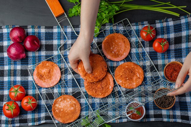 Female hand taking grilled salami slices from grid . 